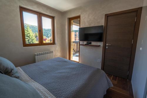 a bedroom with a bed and a flat screen tv at Vista47 Zoned II Kopaonik in Kopaonik