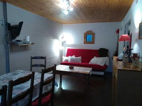 a living room with a red couch and a table at Appartement Chamrousse, 2 pièces, 6 personnes - FR-1-549-54 in Chamrousse