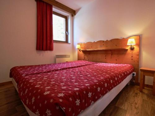um quarto com uma cama com uma colcha vermelha em Appartement Chamrousse, 3 pièces, 6 personnes - FR-1-549-1 em Chamrousse