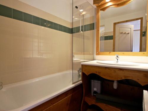 uma casa de banho com um lavatório, uma banheira e um espelho. em Appartement Chamrousse, 3 pièces, 6 personnes - FR-1-549-1 em Chamrousse