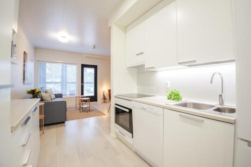 a kitchen with white cabinets and a living room at Apartment Hilmantori kaksio saunalla Kalajoki in Kalajoki