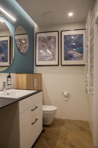 a bathroom with a toilet and three pictures on the wall at Turmalin Apartamenty in Świeradów-Zdrój
