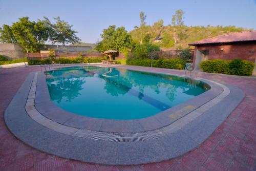 a swimming pool in a yard with a brick house at Gold Nest Rubystone Heritage in Udaipur