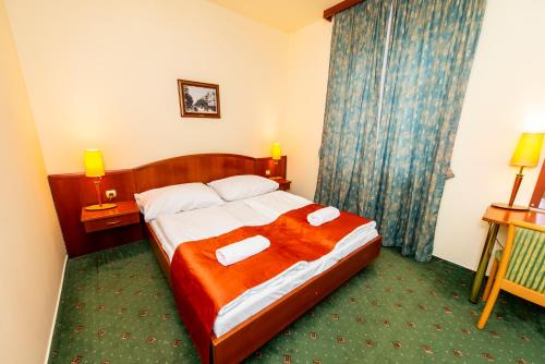 a hotel room with a bed with two towels on it at Gastland M0 Hotel & Conference Center in Szigetszentmiklós