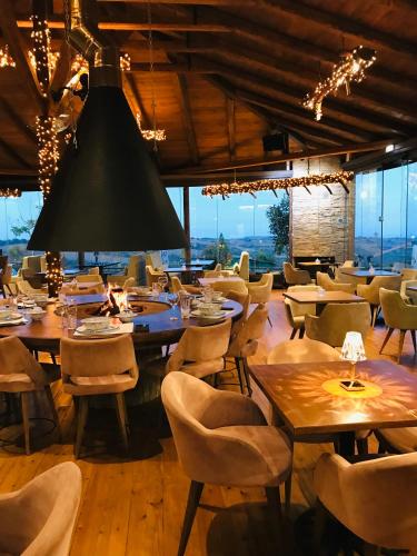 a restaurant with tables and chairs and a large chandelier at 3 Hills Boutique - The Ranch Experience in Trílofos