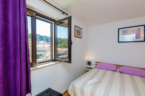 Schlafzimmer mit einem Bett und einem Fenster mit lila Vorhängen in der Unterkunft Apartments & Rooms Mihajica in Cavtat