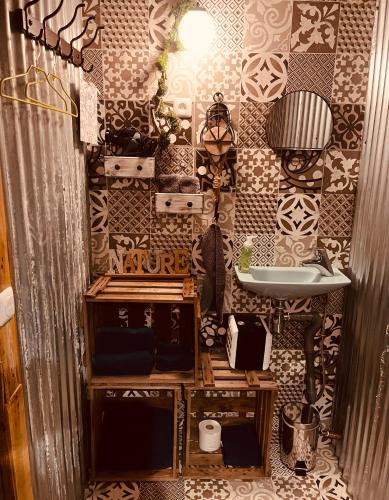 La salle de bains est pourvue d'un lavabo et d'un mur recouvert de carrelage. dans l'établissement Spa La k abane Spa et piscine privatisée, à Blandin