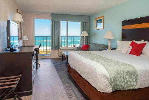 a hotel room with a bed and a desk with a television at Ramada Plaza by Wyndham Nags Head Oceanfront in Kill Devil Hills