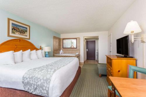 a hotel room with a large bed and a flat screen tv at Ramada Plaza by Wyndham Nags Head Oceanfront in Kill Devil Hills