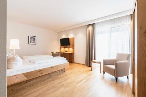 a bedroom with a bed and a chair and a television at Hotel & Gasthaus Löwen in Waldkirch