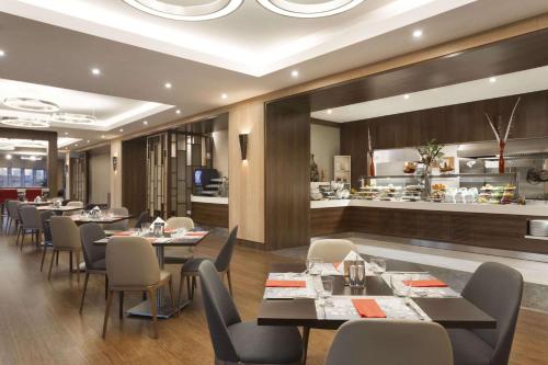 een restaurant met tafels en stoelen en een keuken bij Ramada Encore Istanbul Bayrampasa in Istanbul
