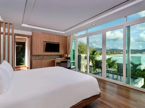 a bedroom with a large bed and a large window at Novotel Phuket Kamala Beach in Kamala Beach
