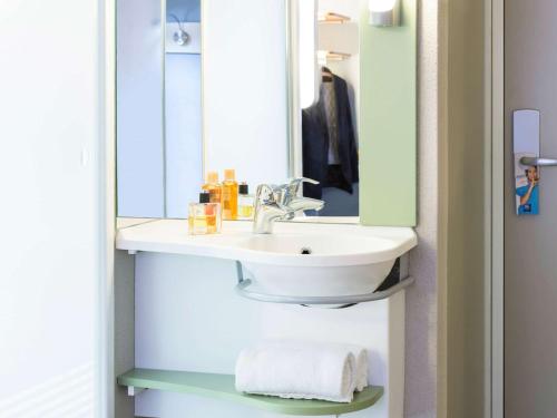 a bathroom with a sink, mirror, and towel rack at ibis budget Zurich Airport in Glattbrugg