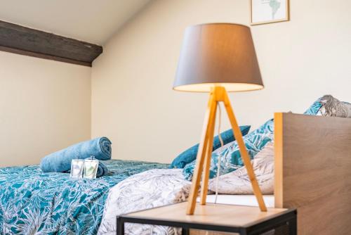 a lamp on a table next to a bed at Delight - GOLDEN TREE - Clim - 20 min St-Croix & Center Parcs in Sarrebourg