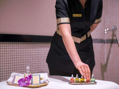 una mujer en una cocina preparando comida en una mesa en Hotel de la Cité & Spa MGallery en Carcasona