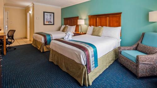 a hotel room with two beds and a chair at The Sandbar Hotel, Trademark Collection by Wyndham in Myrtle Beach