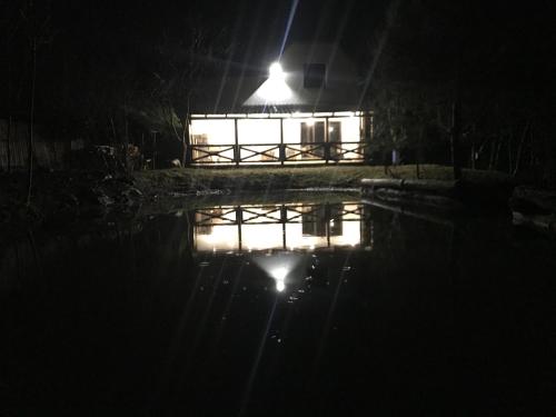 a house lit up at night with a pool of water at Rest House 6A in Obava