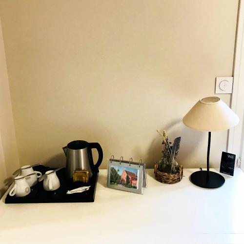 une table avec une lampe, une bouilloire et une photo dans l'établissement Le Clos Fleuri - Maison Vigier, à Maringues