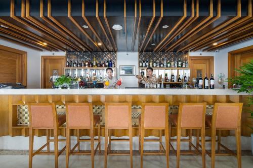 a bar in a restaurant with orange chairs at Paris Deli Danang Beach Hotel in Da Nang