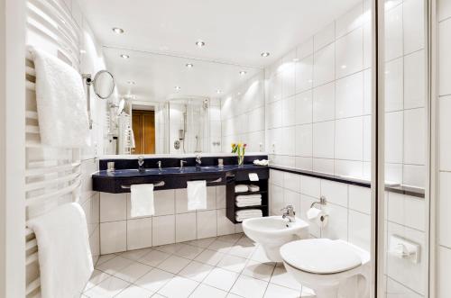 ein weißes Bad mit einem WC und einem Waschbecken in der Unterkunft Strandhotel Juister Hof in Juist