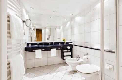 a white bathroom with a toilet and a sink at Strandhotel Juister Hof in Juist