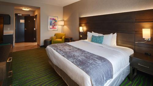 a hotel room with a large bed and a chair at Best Western Plus Prien Lake Hotel & Suites - Lake Charles in Lake Charles