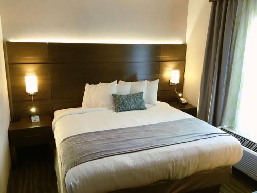 a large bed in a hotel room with two lamps at Best Western Plus Prien Lake Hotel & Suites - Lake Charles in Lake Charles