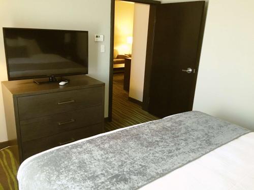 a bedroom with a bed and a flat screen tv at Best Western Plus Prien Lake Hotel & Suites - Lake Charles in Lake Charles