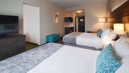 a hotel room with two beds and a flat screen tv at Best Western Plus Prien Lake Hotel & Suites - Lake Charles in Lake Charles