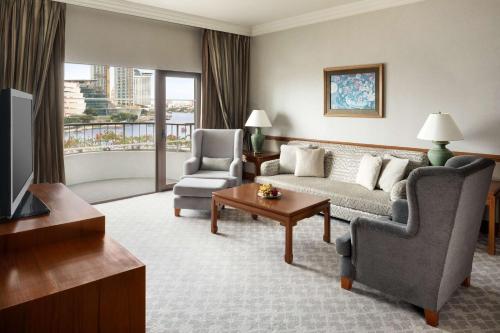 a living room with a couch and two chairs and a television at Shangri-La Bangkok in Bangkok