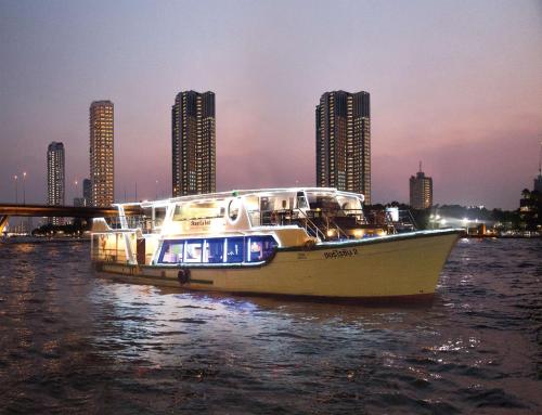 a boat in the water with buildings in the background at Shangri-La Bangkok in Bangkok
