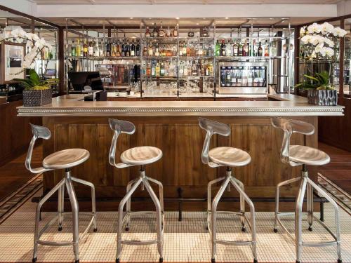 a bar with three stools in front of a counter at Hôtel Paris Bastille Boutet - MGallery in Paris