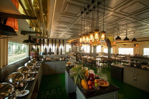 Polo Floatel Kolkata في كولْكاتا: غرفة طعام كبيرة بها طاولات وكراسي وثريات
