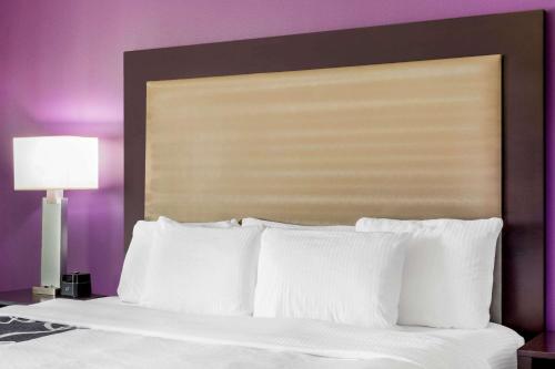 a bed with white pillows and a purple wall at La Quinta by Wyndham McAllen Convention Center in McAllen