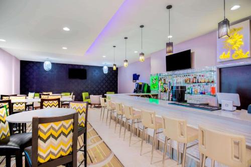 a restaurant with a bar with tables and chairs at La Quinta by Wyndham McAllen Convention Center in McAllen
