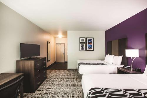 a hotel room with two beds and a flat screen tv at La Quinta by Wyndham Lubbock South in Lubbock