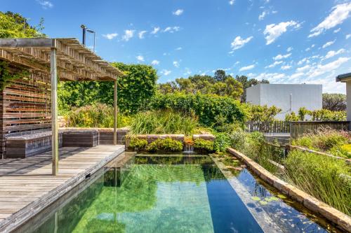 een zwembad in een tuin met een houten terras bij Solar-Powered Mountain Retreat with Natural Pool in Kaapstad