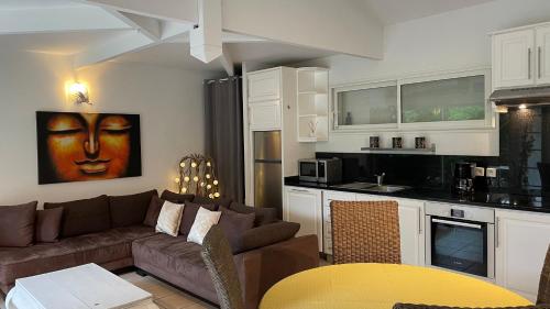 un salon avec un canapé et une cuisine dans l'établissement Maison Blanche, à Lanton