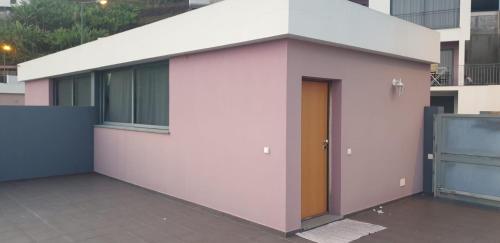 a pink and white building with a yellow door at D Henriques House in Câmara de Lobos