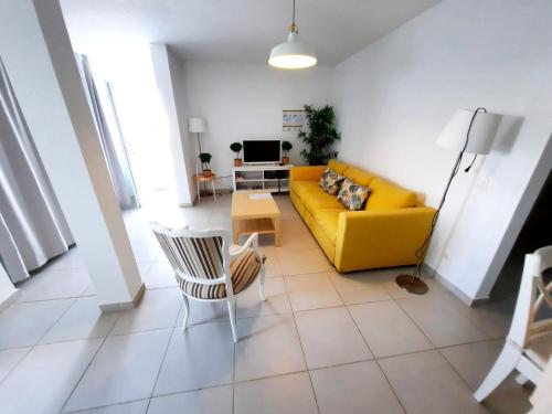 a living room with a yellow couch and a table at Duna Parque Beach Club - Duna Parque Resorts & Hotels in Vila Nova de Milfontes
