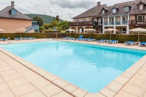 - une grande piscine dans un complexe avec des chaises et des parasols dans l'établissement Résidence Les Belles Rives - maeva Home, à Argentat