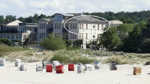 a group of chairs sitting on the beach in front of a building at Villa Anna Meerblick erste Reihe in Ahlbeck