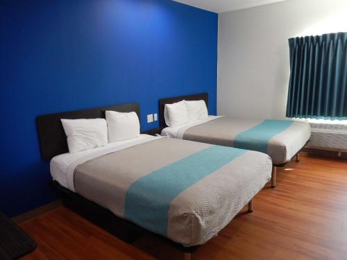 two beds in a room with a blue wall at Knights Inn Houston in Houston