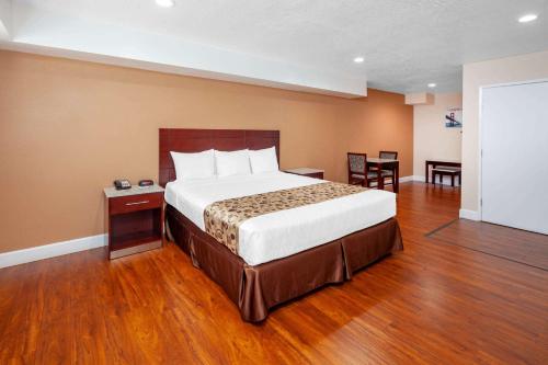 1 dormitorio con 1 cama grande, mesa y sillas en Travelodge by Wyndham Harbor City, en Harbor City