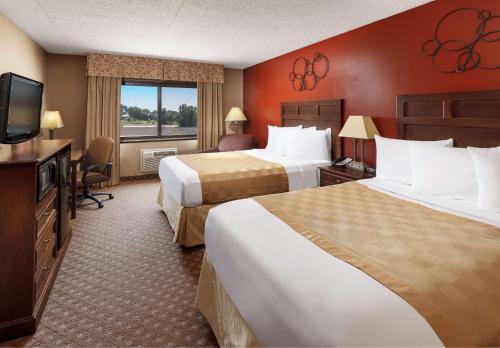 a hotel room with two beds and a flat screen tv at Roosevelt Grand Dakota SureStay Collection by Best Western in Dickinson