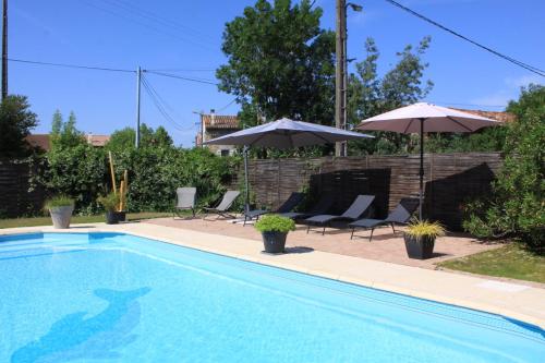 a swimming pool with two umbrellas and two chairs at Gite La Luciole in Tourtrol