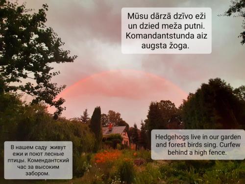 a rainbow in the sky over a field with a sign at Champêtre Park View Apartments in Rīga