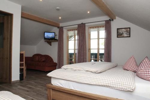 a bedroom with a bed and a couch and windows at Berggasthof Pechhäusl in Berchtesgaden