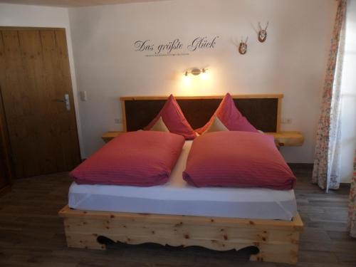 a bedroom with a bed with red pillows on it at Berggasthof Pechhäusl in Berchtesgaden