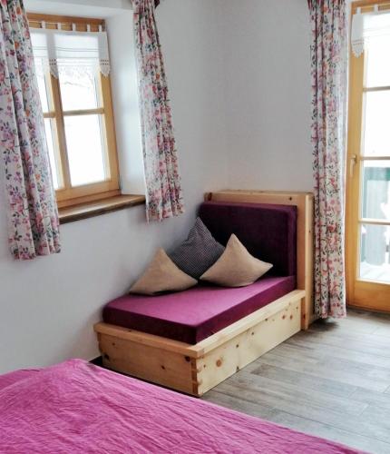 a bedroom with a bed with a purple mattress and windows at Berggasthof Pechhäusl in Berchtesgaden
